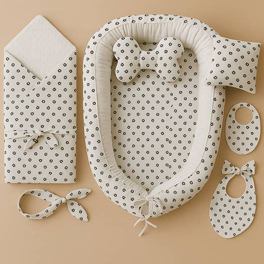  Baby set s hnízdečkem obšitým bílou minky látkou s puntíky a látkou s drobnými černými tlapkami, doplněný zavinovačkou, polštářkem a bryndáčky.